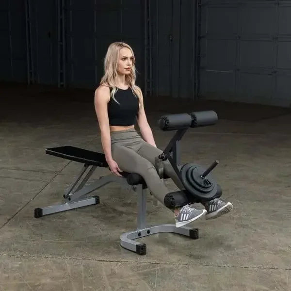 Frau trainiert auf Hantelbank mit Beinpress-Funktion im Fitness-Studio