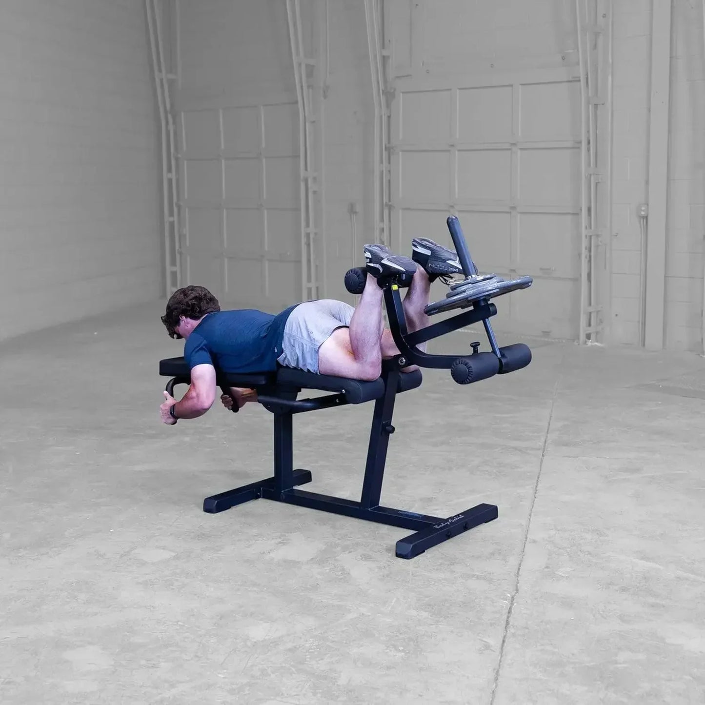 Mann trainiert Beinbeuger auf Fitnessbank im Homegym – Kraftstation für effektives Beintraining