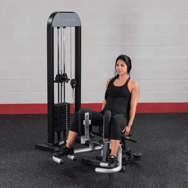Frau trainiert an Kraftstation mit Beinpress und Kabelzug im Fitnessstudio