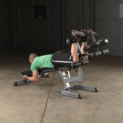 Mann trainiert Beinbeuger auf Hantelbank im Homegym mit Kraftstation
