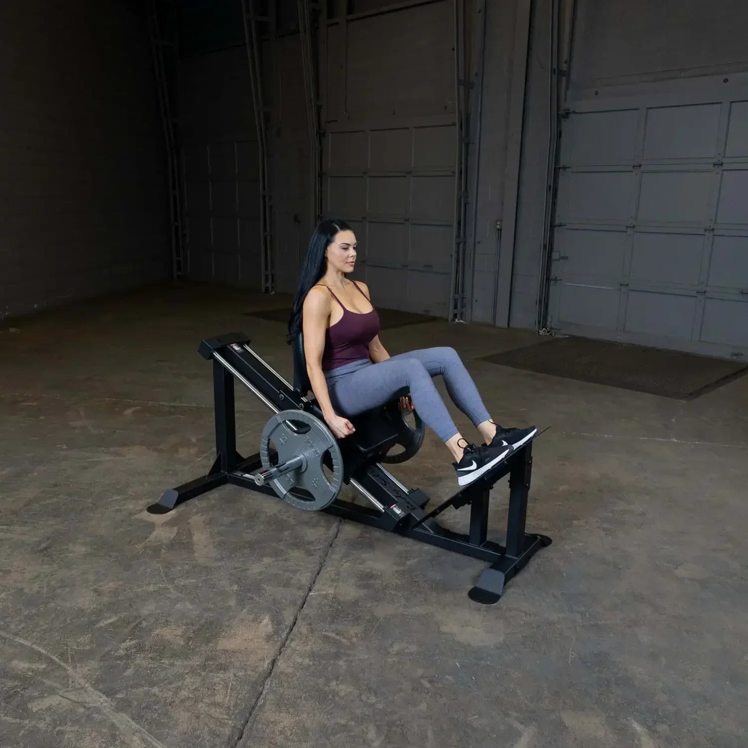 Frau trainiert Beine auf Fitness-Kraftgerät in Garage, ideal für Homegym & Studio