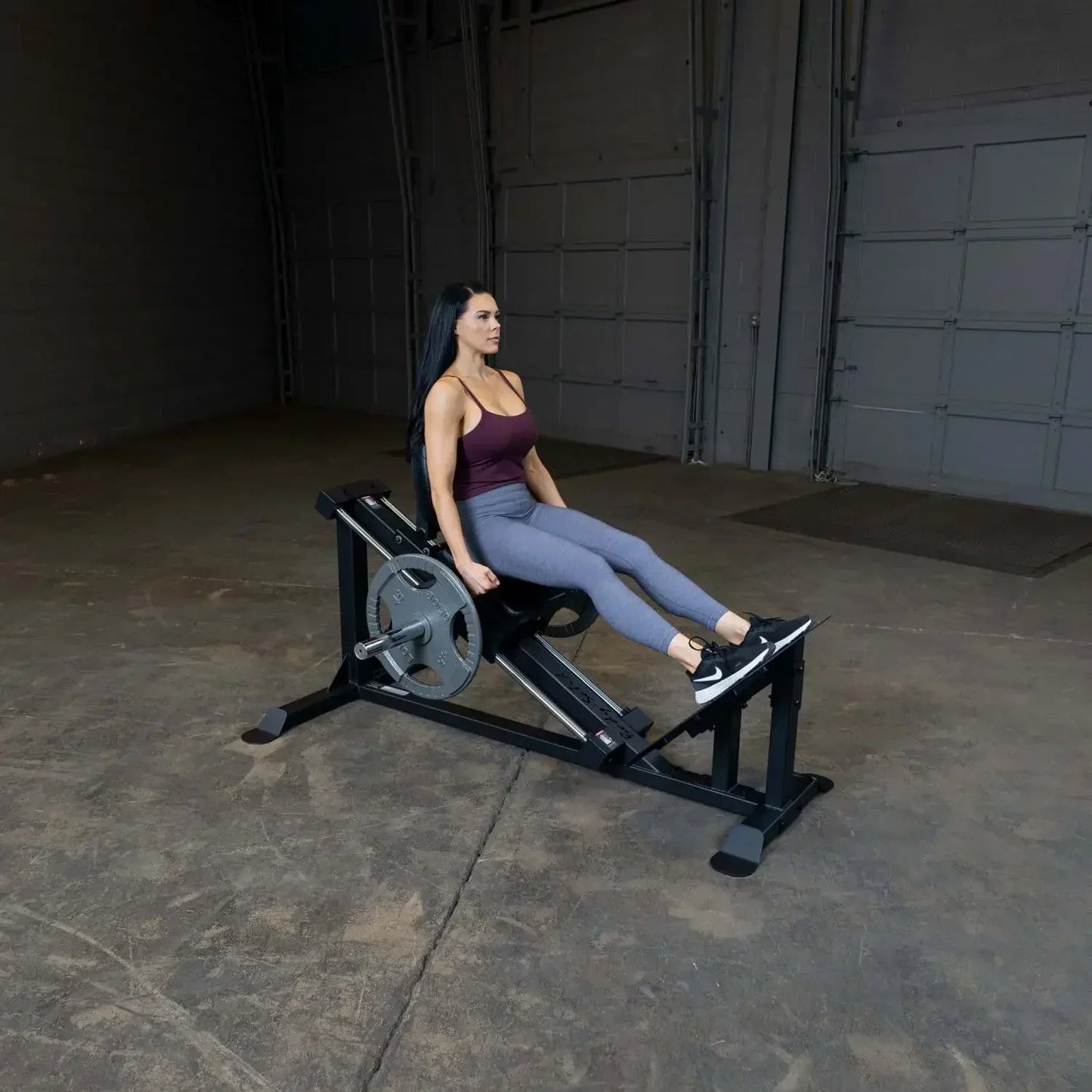 Frau trainiert Beine mit Beinpresse im Fitnessstudio, Kraftstation für Homegym & Studio