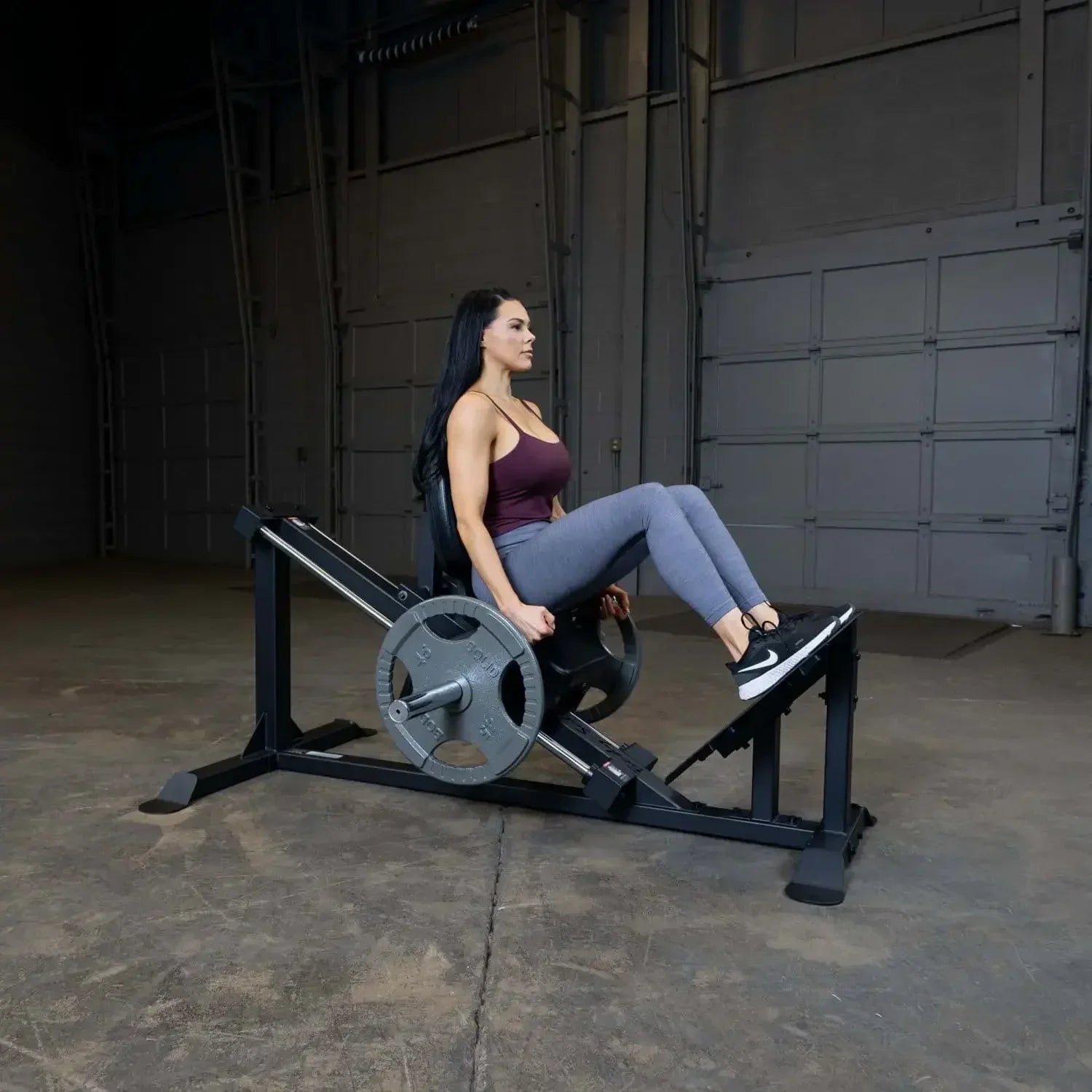 Frau trainiert auf einer Beinpresse im Fitnessstudio mit Hantelscheiben