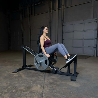 Frau trainiert auf einer Beinpresse im Fitnessstudio mit Hantelscheiben