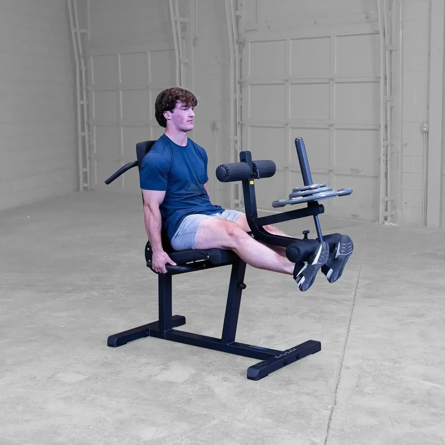 Mann trainiert Beine auf Hantelbank mit Beinpresse im Homegym, Fitness-Kraftgerät für Kraftsport