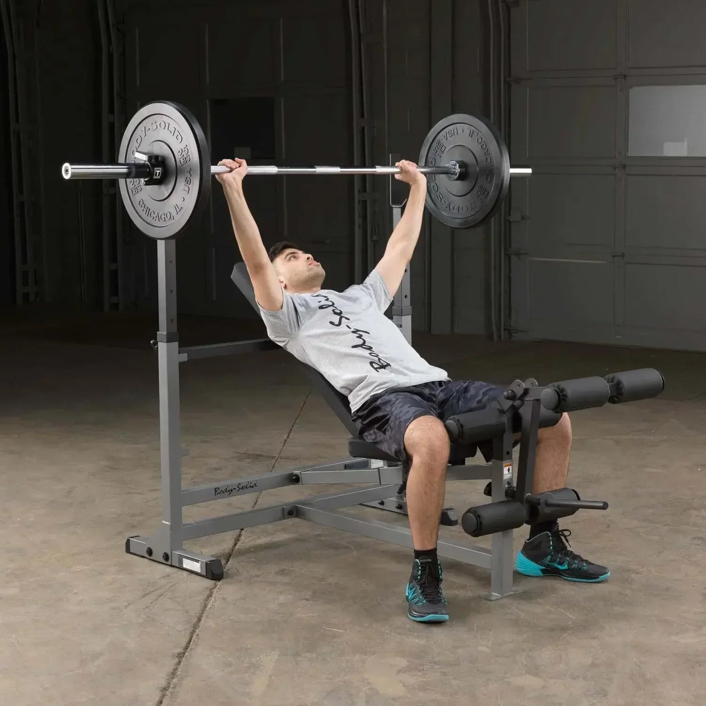 Mann trainiert Bankdrücken auf Hantelbank mit Barbell im Homegym – Fitness-Kraftgerät