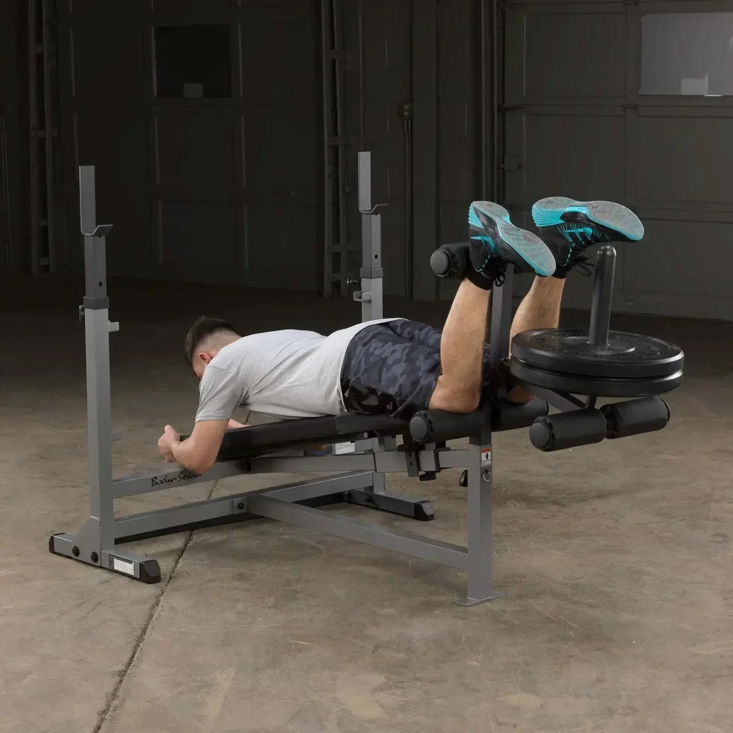 Mann trainiert Beinbeuger auf Hantelbank im Homegym mit Kraftstation
