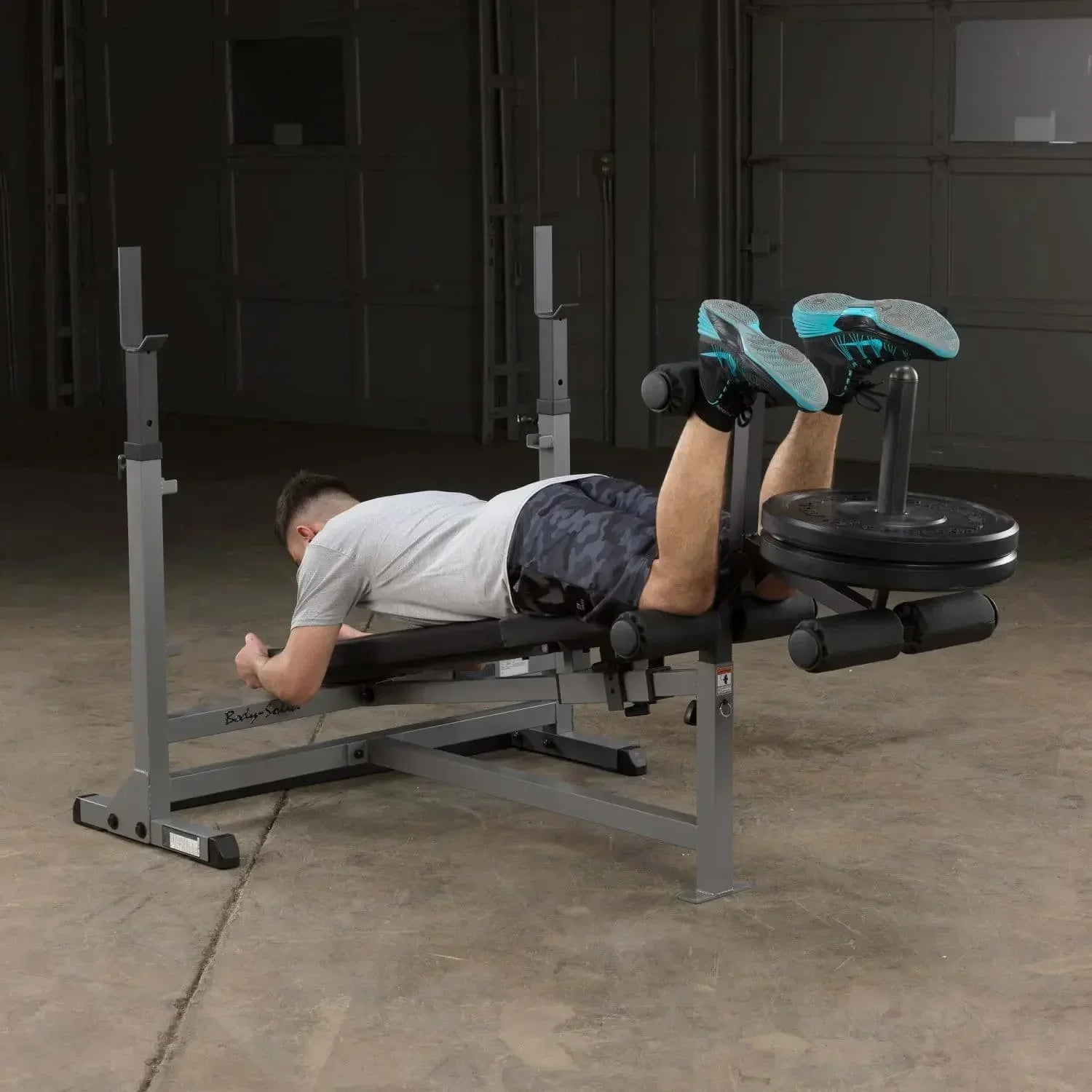 Mann trainiert Beinbeuger auf Hantelbank im Homegym mit Kraftstation