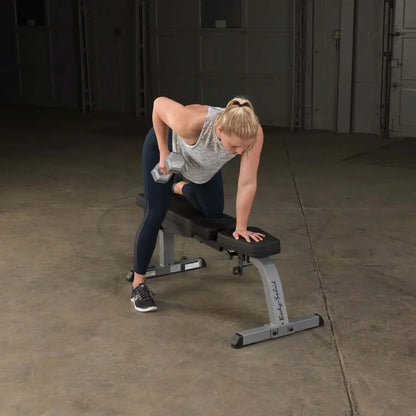 Frau trainiert mit Hantel auf Fitnessbank im Homegym – Krafttraining mit Hantelbank