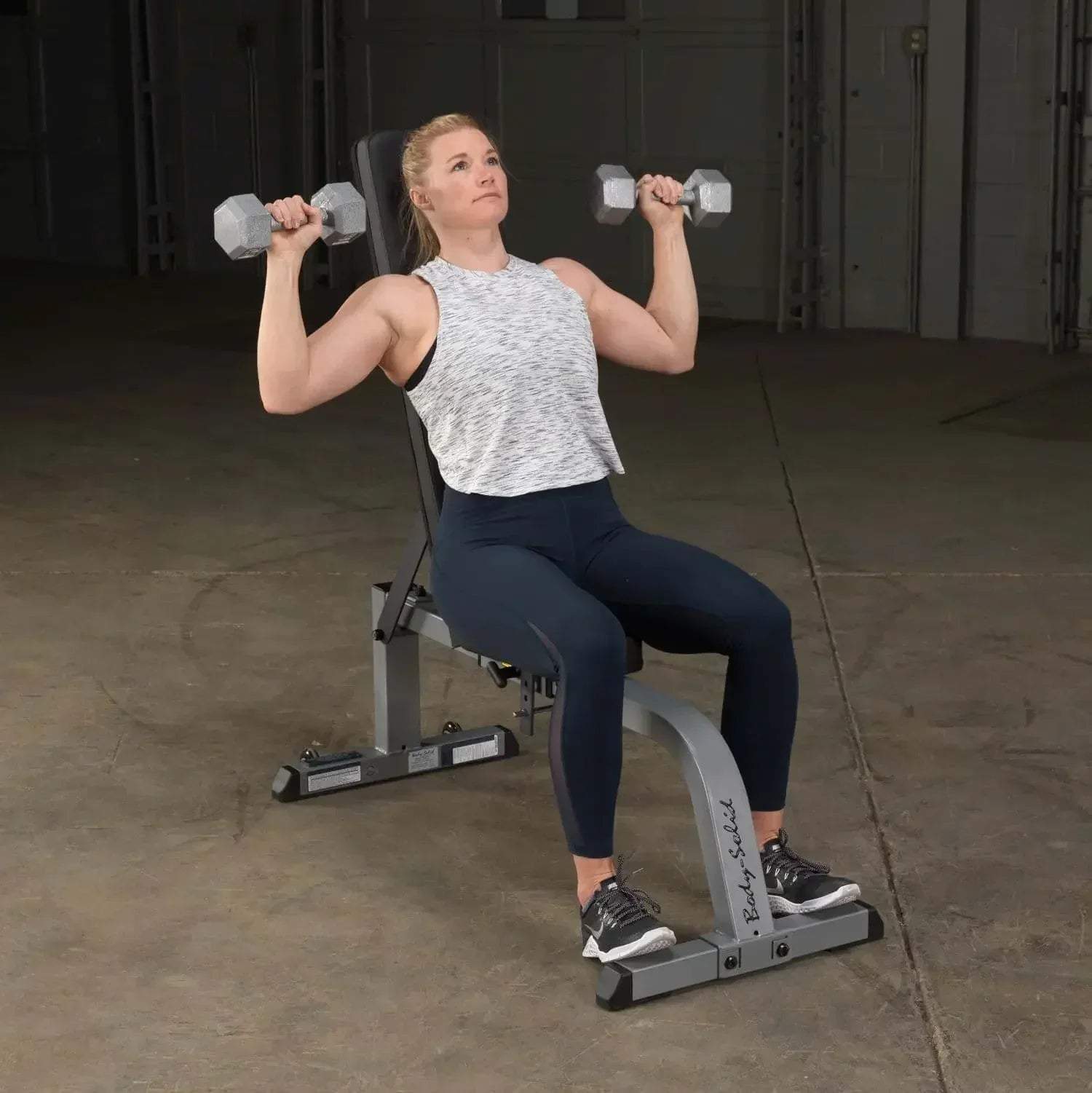 Frau trainiert mit Hanteln auf Hantelbank im Homegym – Krafttraining mit Fitnessgeräten