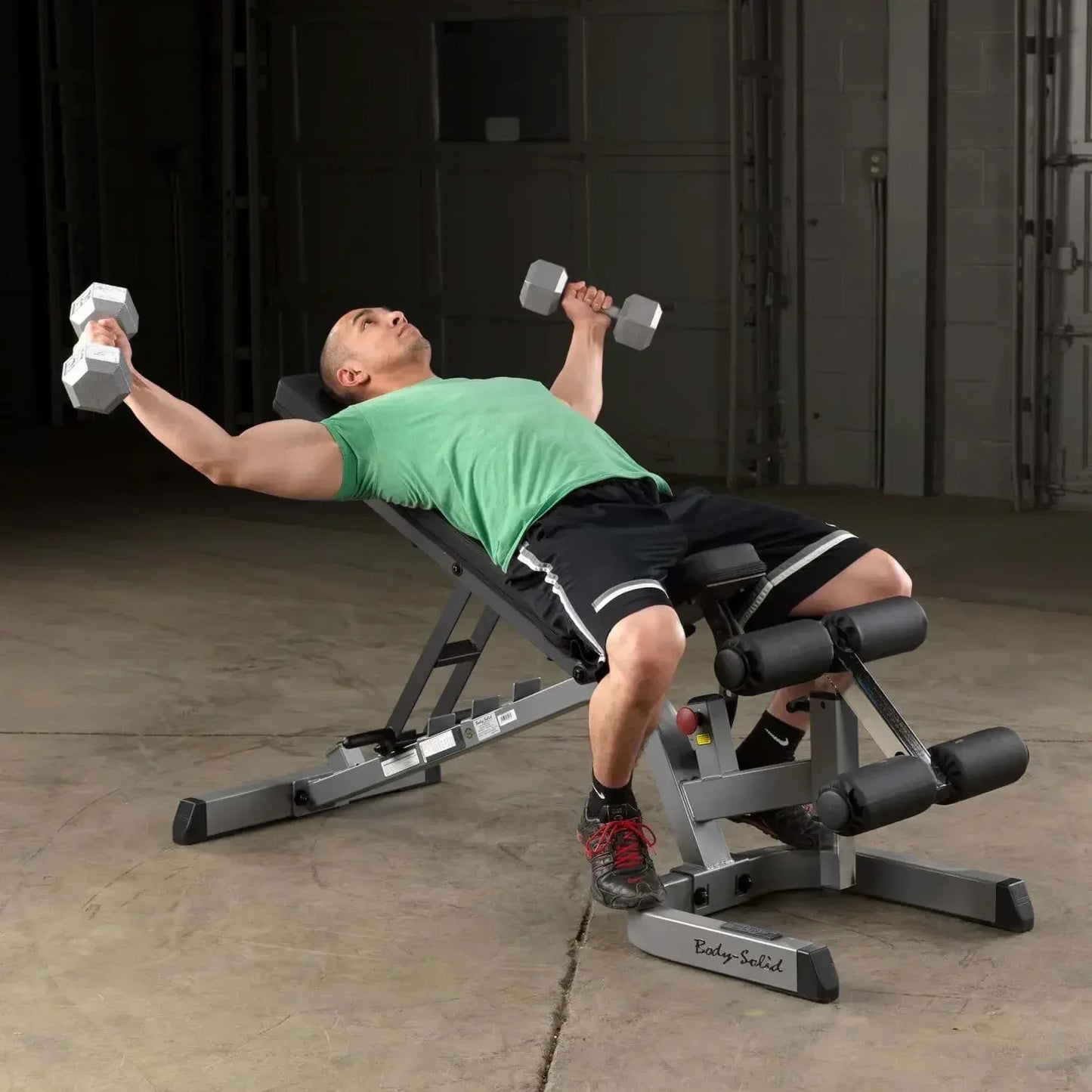 Mann trainiert mit Hanteln auf einer Hantelbank im Homegym – Fitness-Kraftgeräte für effektives Training