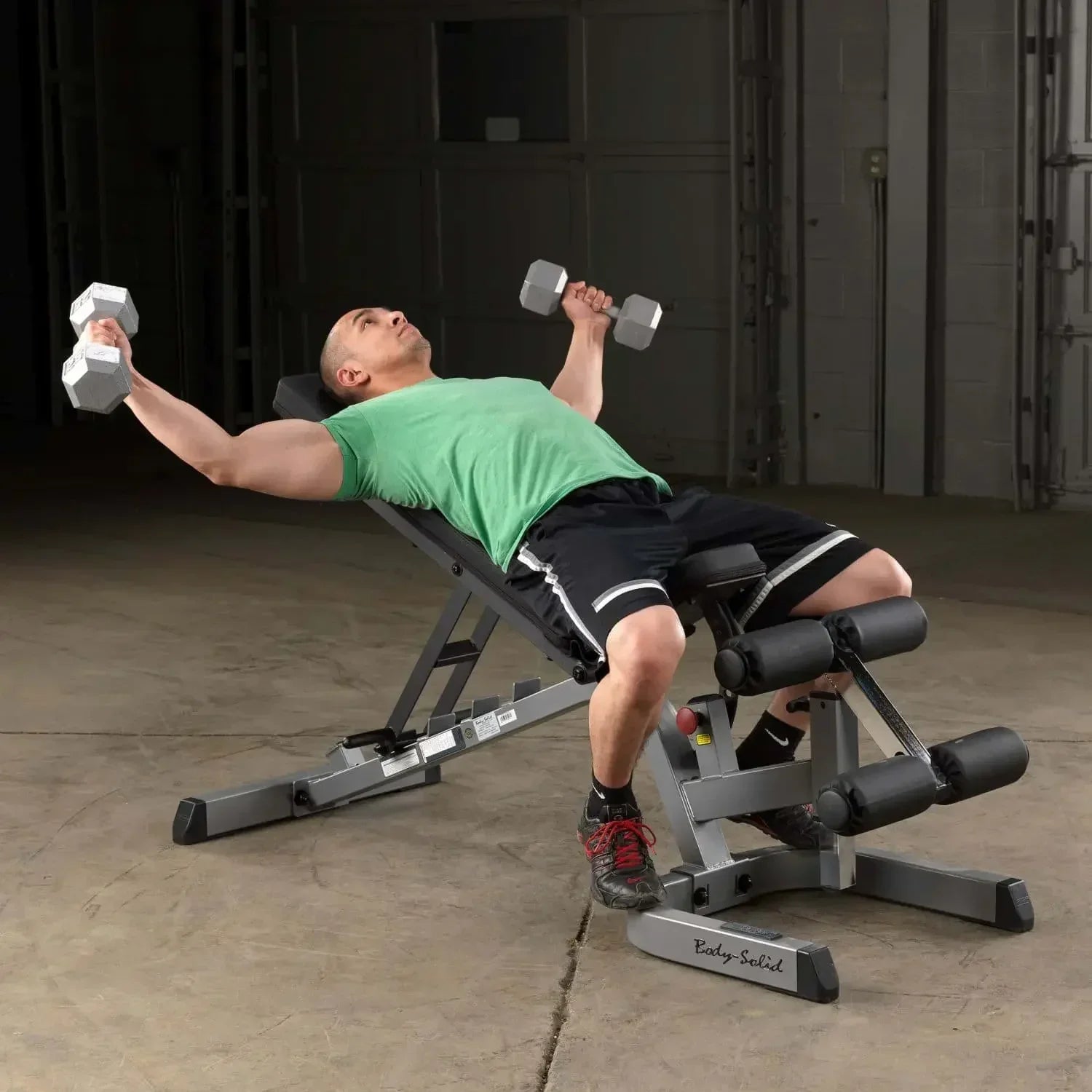 Mann trainiert mit Hanteln auf einer Hantelbank im Homegym – Fitness-Kraftgeräte für effektives Training
