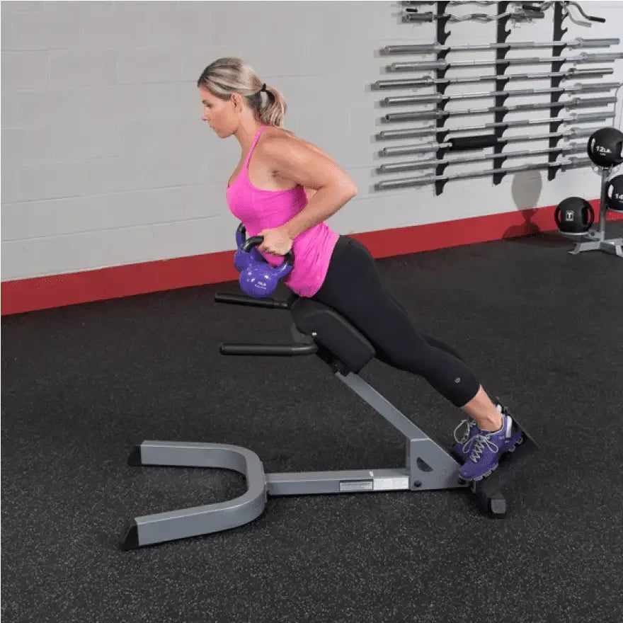 Frau trainiert mit Kettlebell auf Hantelbank im Fitnessstudio – Krafttraining & Homegym Equipment