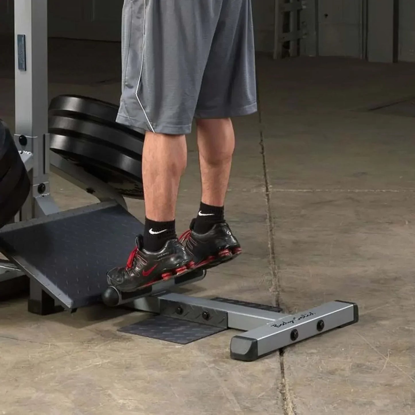 Mann trainiert Beine auf Fitness-Stepper mit Hantelbank im Homegym