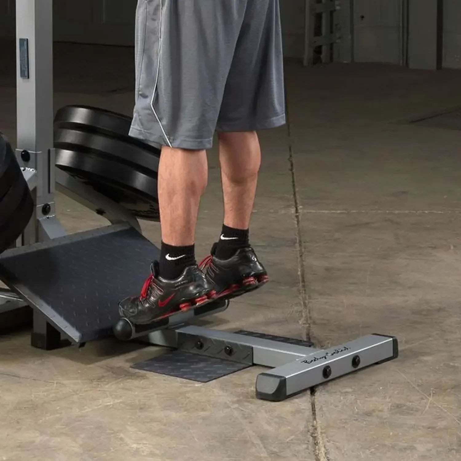 Mann trainiert Beine auf Fitness-Stepper mit Hantelbank im Homegym