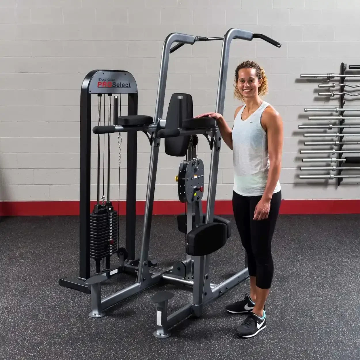 Frau neben multifunktionaler Kraftstation mit Kabelzug und Gewichtsscheiben im Fitnessstudio