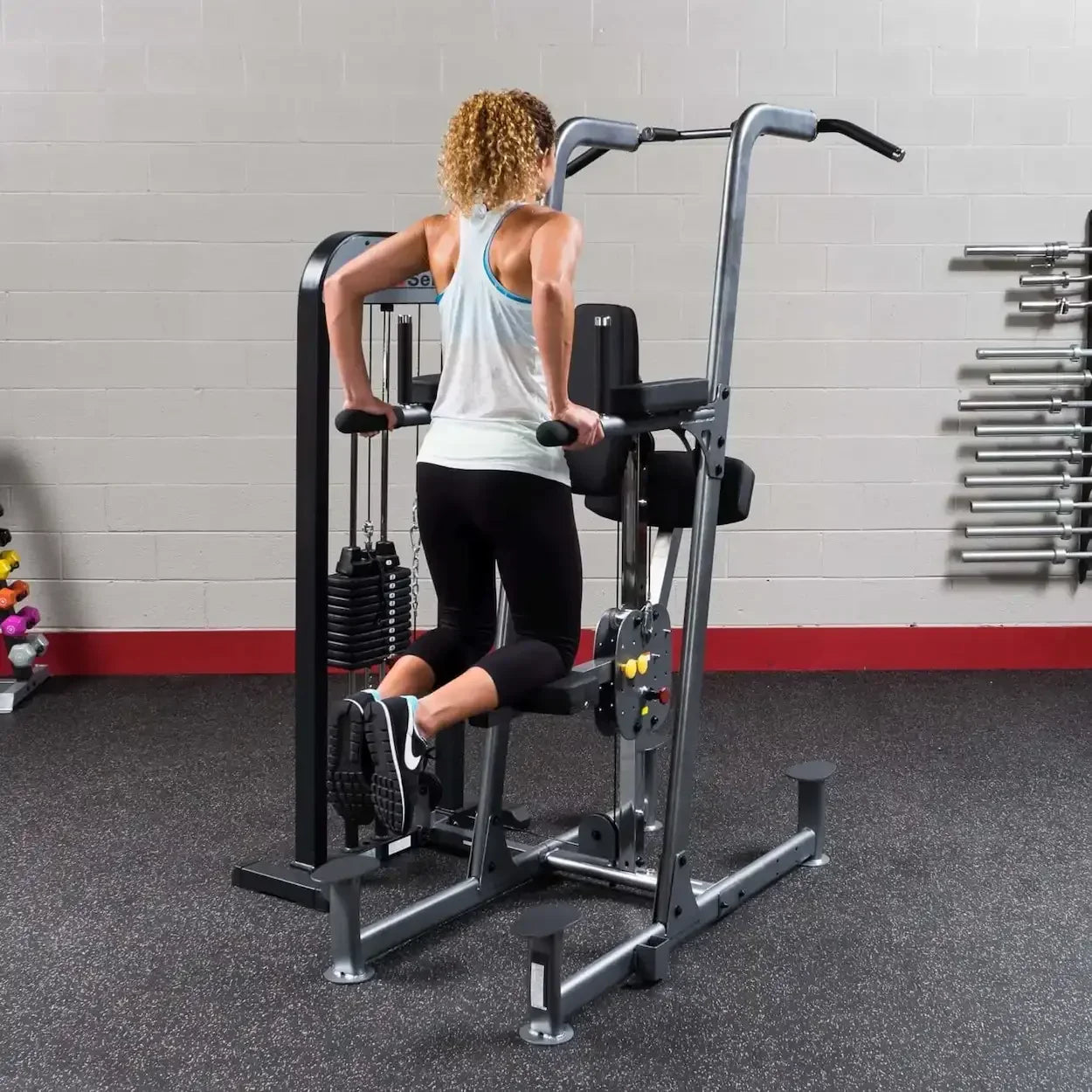 Frau trainiert an Kraftstation im Fitnessstudio mit Hanteln und Gewichten