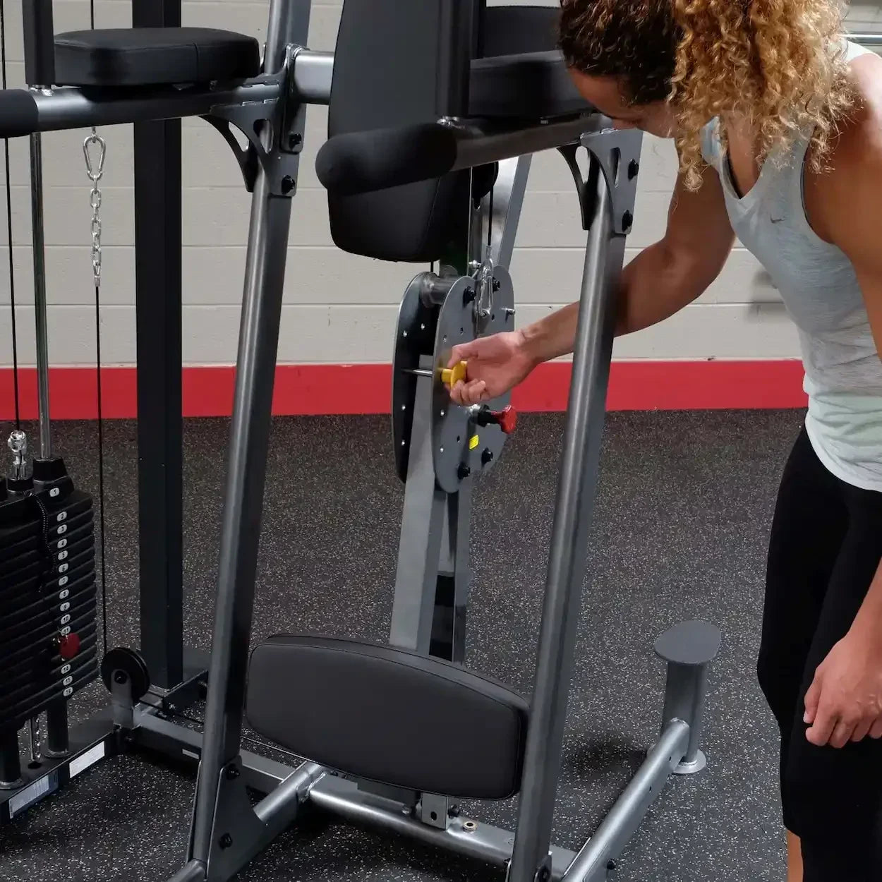 Frau justiert Gewicht an Kraftstation im Fitnessstudio – ideal für Homegym & Studio-Training