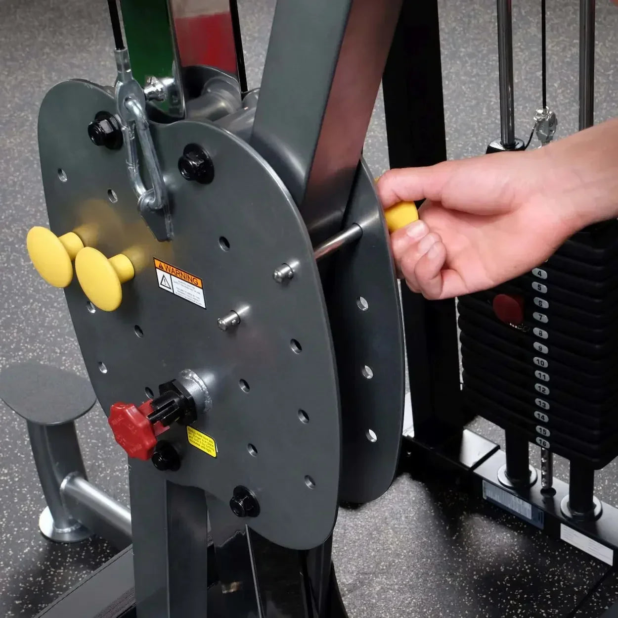 Hand justiert Gewicht an Kraftstation mit gelben Knöpfen für Homegym-Training