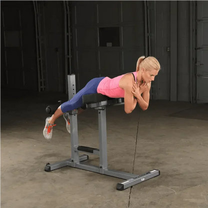 Frau trainiert Rückenübungen auf Hantelbank im Homegym – Fitness-Kraftgeräte für effektives Training