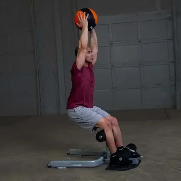 Mann trainiert mit Medizinball auf Fitnessbank – Krafttraining zu Hause oder im Studio