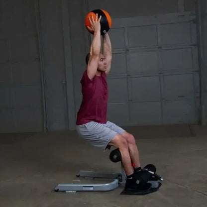 Mann trainiert mit Medizinball auf Fitnessbank – Krafttraining zu Hause oder im Studio