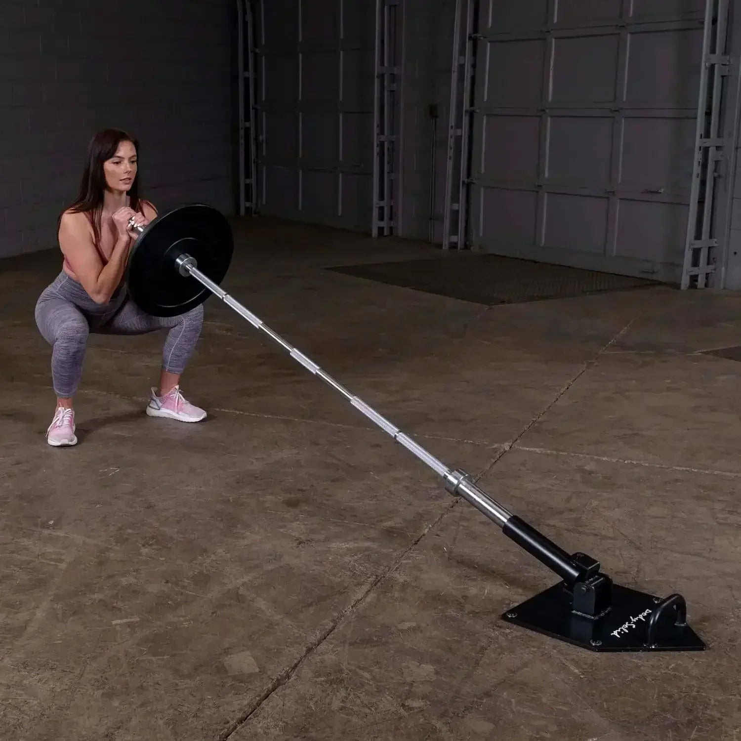 Frau trainiert mit Langhantel und Bodenhalterung im Fitnessstudio – Krafttraining Equipment
