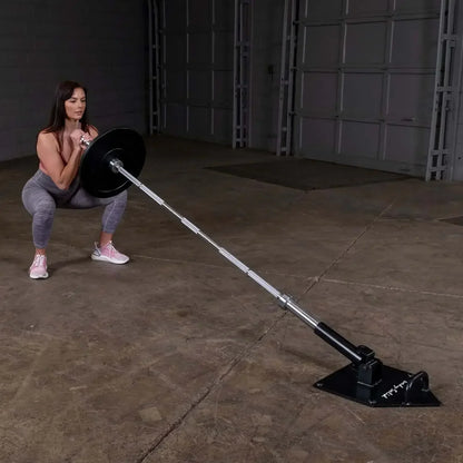 Frau trainiert mit Langhantel und Bodenhalterung im Fitnessstudio – Krafttraining Equipment