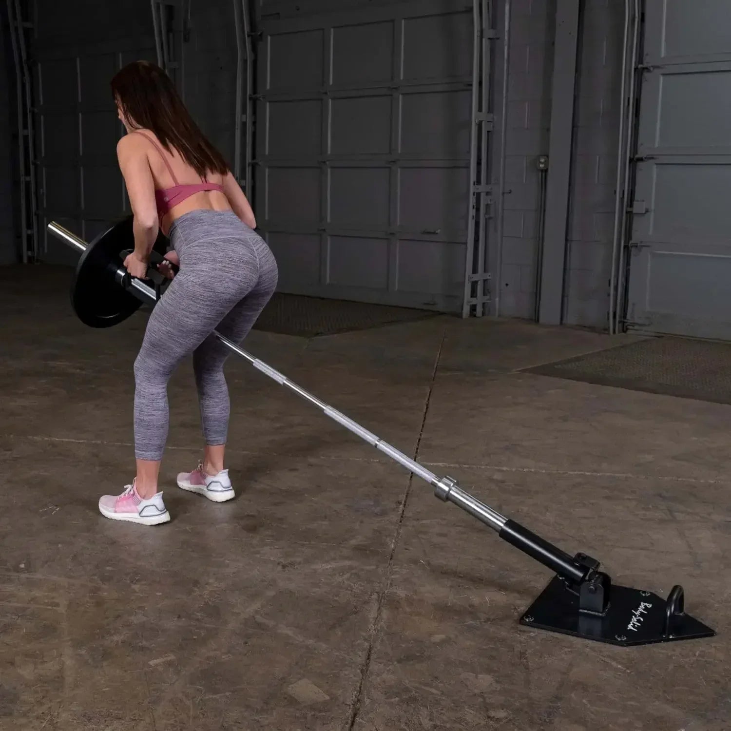 Frau trainiert mit Langhantel und Bodenanker im Homegym – Kraftsport Equipment für effektives Training