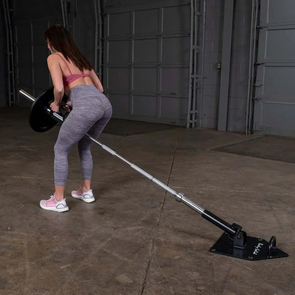 Frau trainiert mit Langhantel und Bodenanker im Homegym – Kraftsport Equipment für effektives Training
