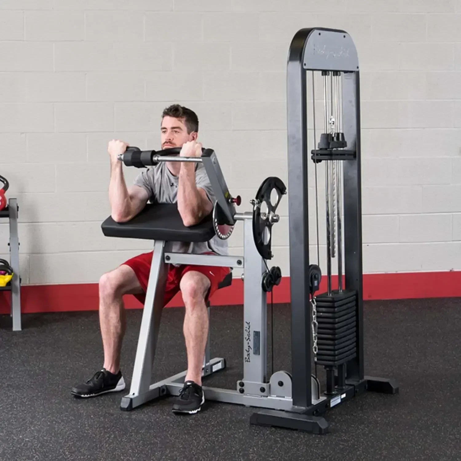 Mann trainiert Bizeps an Kraftstation mit Kabelzug im Fitnessstudio