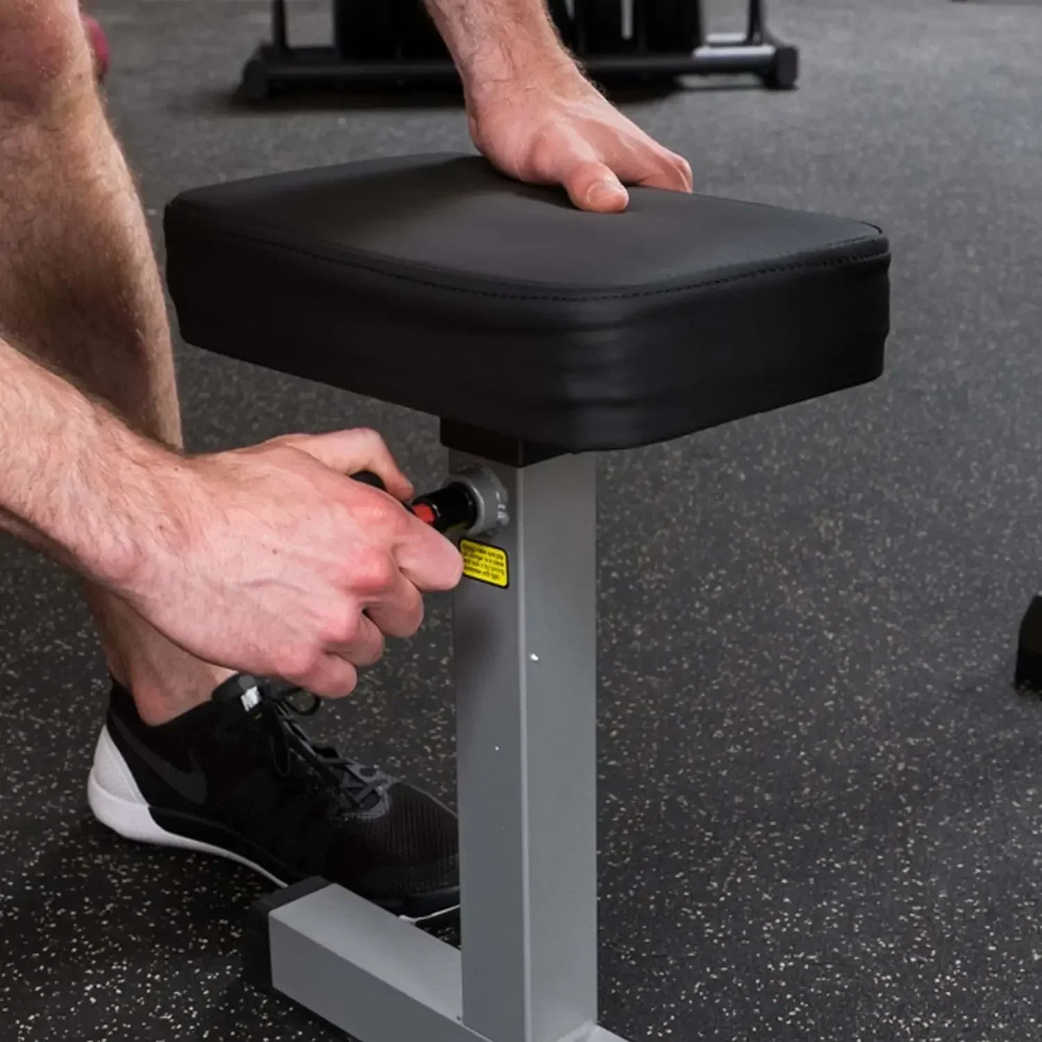 Mann justiert höhenverstellbare Hantelbank für Krafttraining im Fitnessstudio