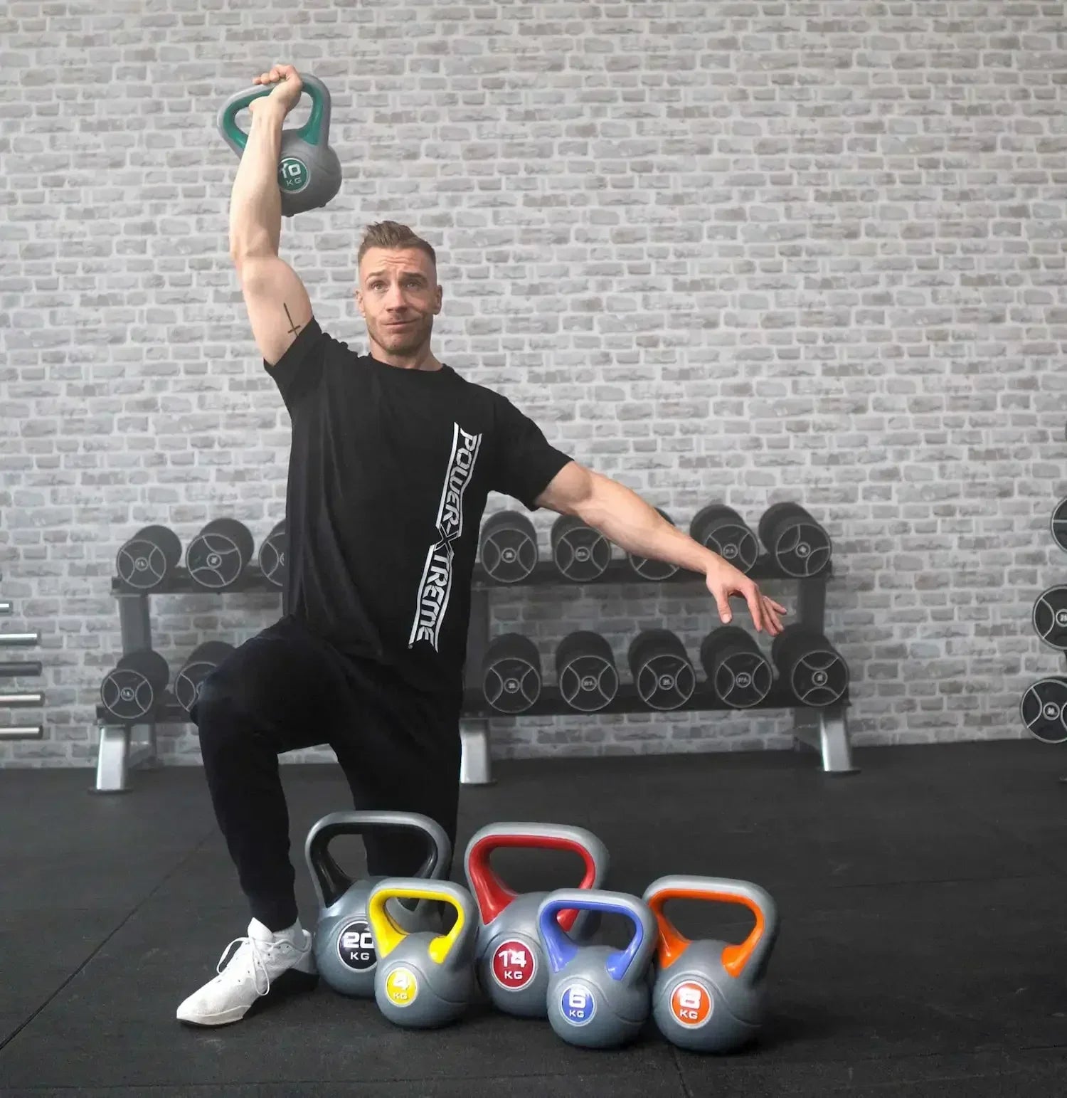Mann trainiert mit 10 kg Kettlebell vor Hantelbank, weitere Kettlebells im Vordergrund für Homegym & Studio