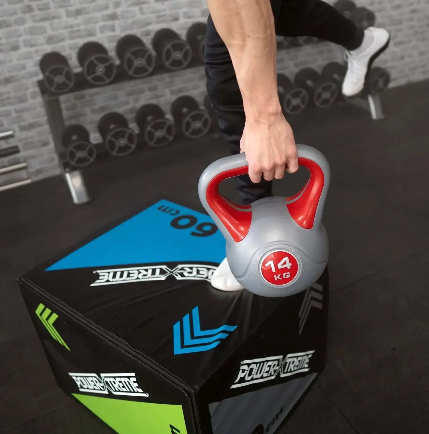 14 kg Kettlebell auf Power-Xtreme Box, Fitness-Training im Homegym mit Hanteln im Hintergrund