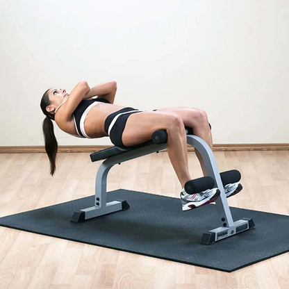 Frau trainiert Bauchmuskeln auf Hantelbank im Homegym mit Fitnessmatte