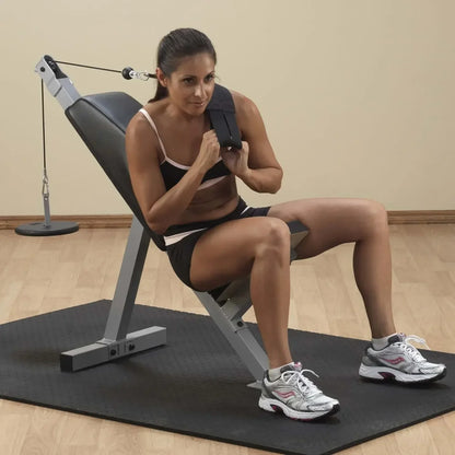 Frau trainiert mit Kabelzug an Fitnessbank für Homegym, Kraftstation mit Trainingsmatte