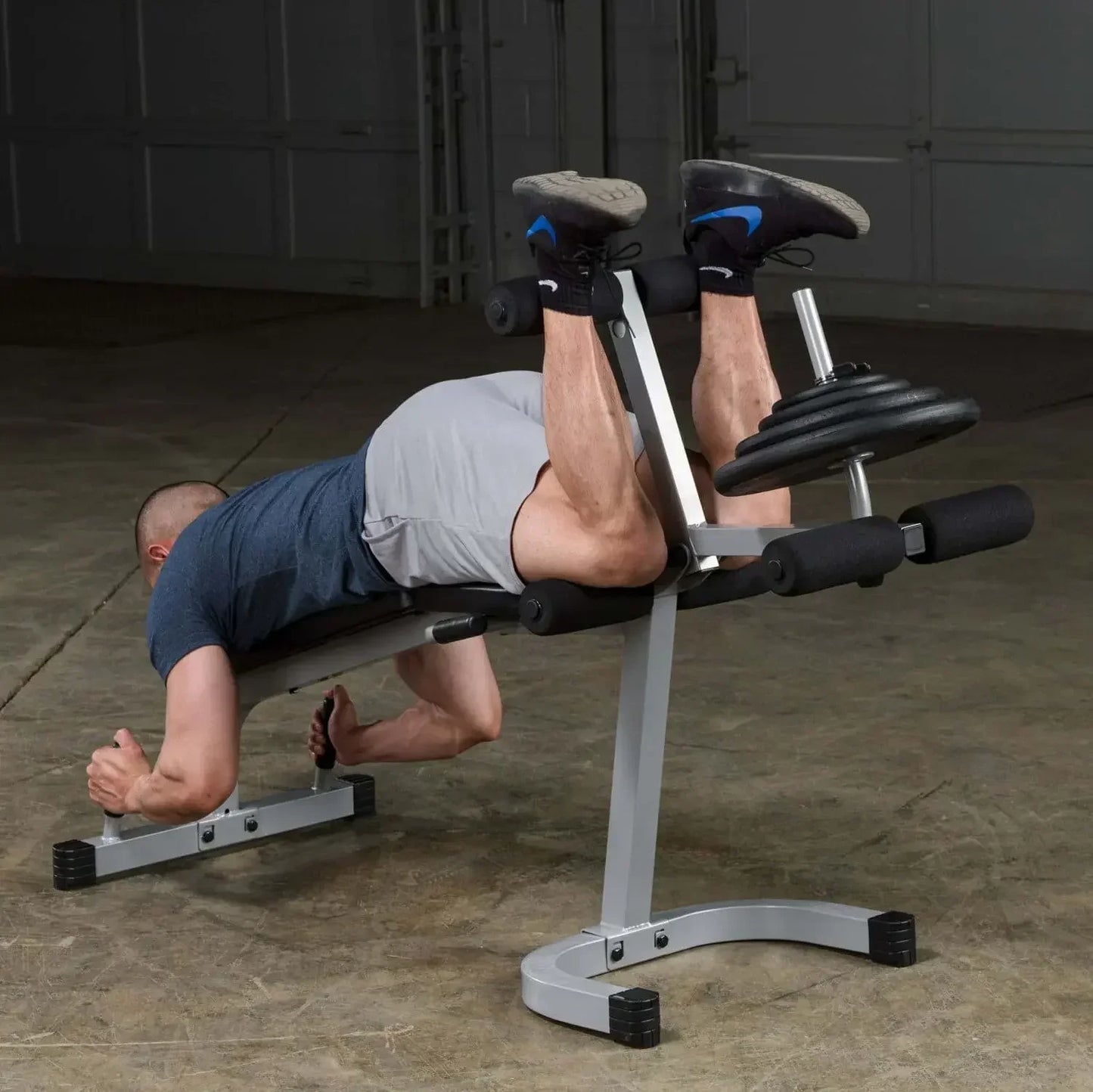 Mann trainiert Beine auf Hantelbank mit Gewichten im Homegym – Fitness-Kraftgeräte
