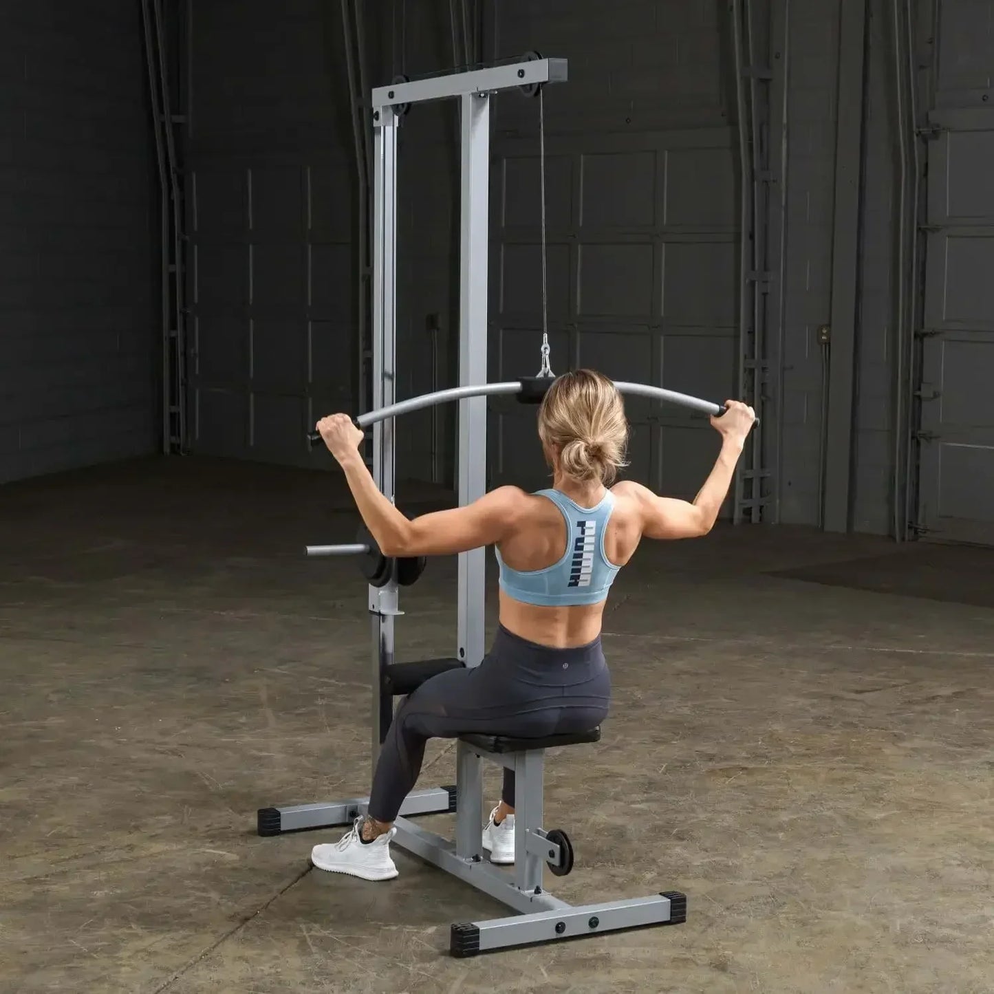 Frau trainiert Rücken mit Kraftstation im Homegym – Fitness-Kraftgerät für effektives Training