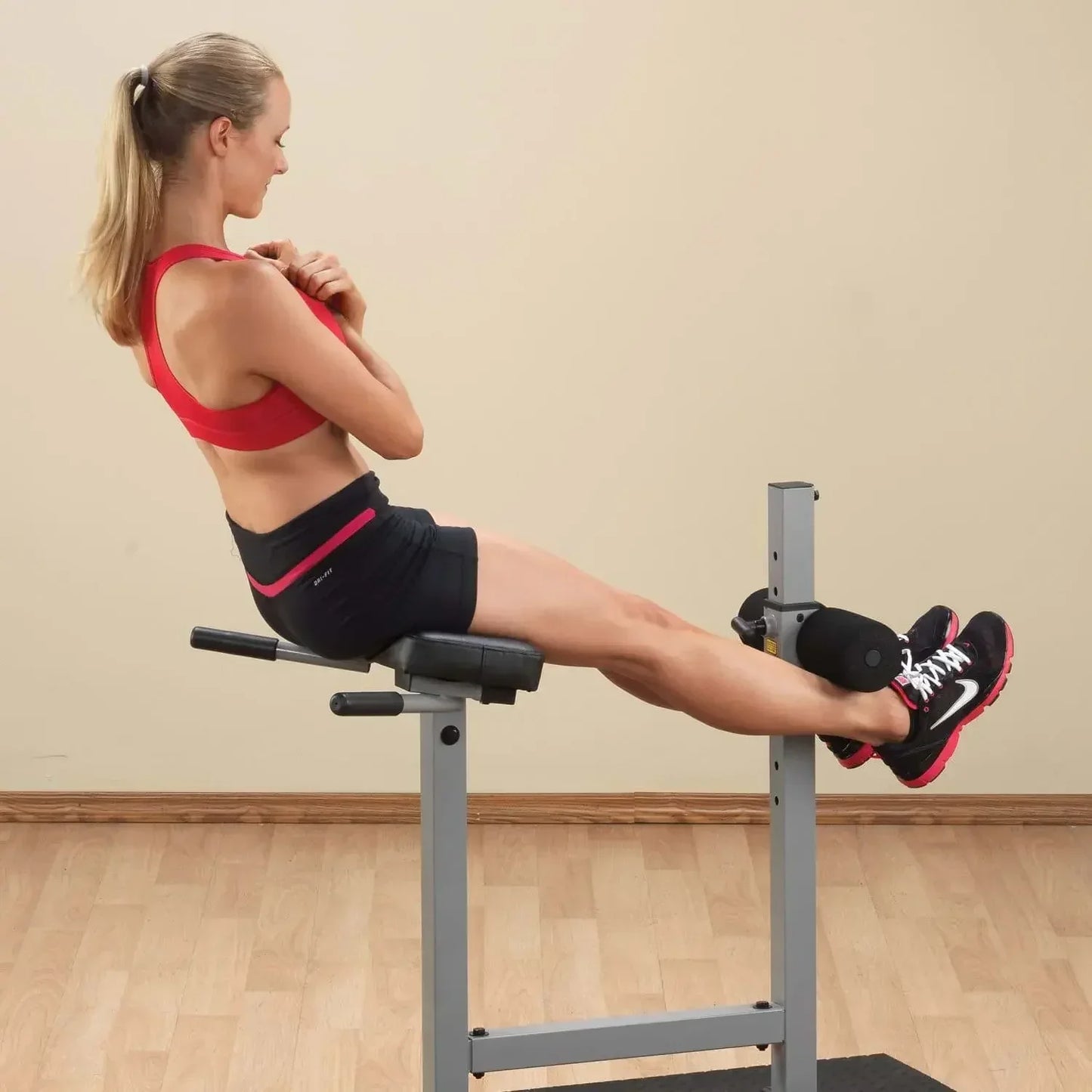 Frau trainiert Bauchmuskeln auf Hantelbank mit Beinhalterung – Fitness-Kraftgerät für Homegym