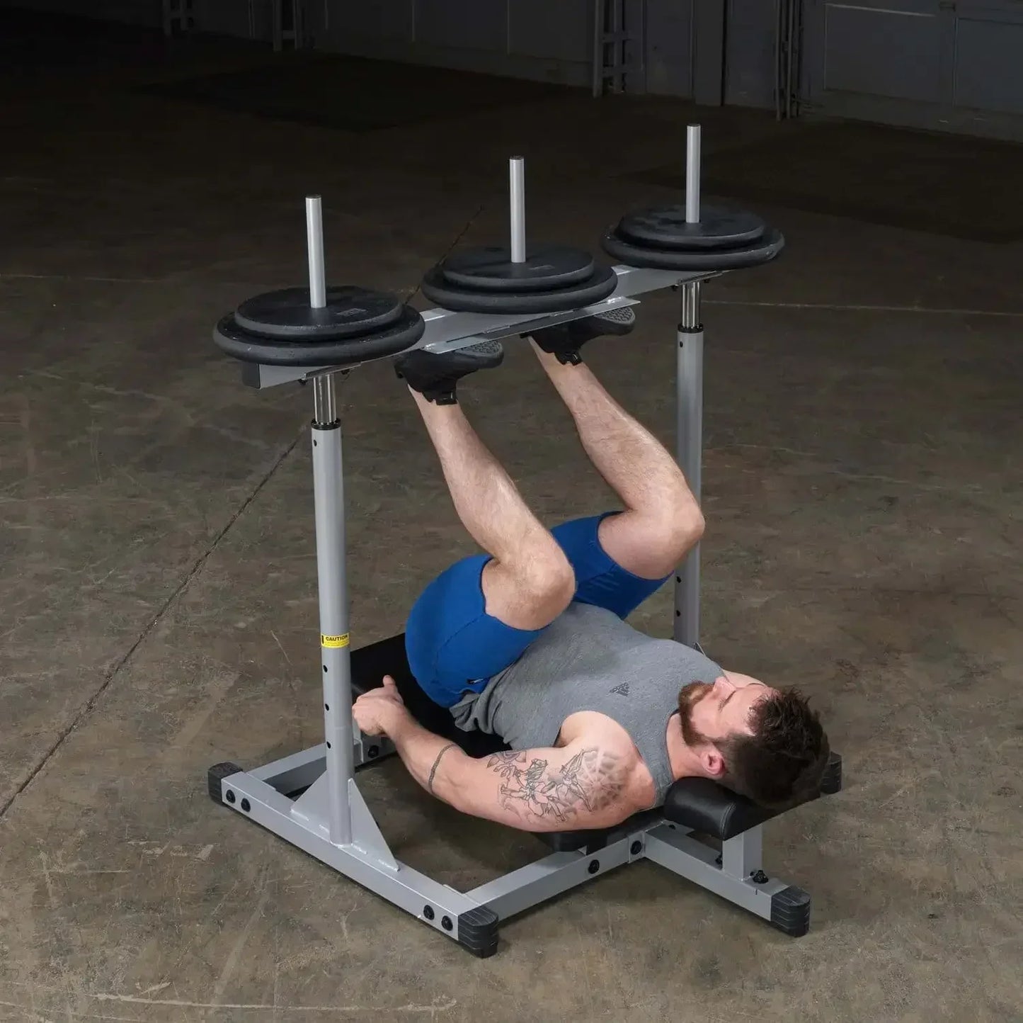 Mann trainiert Beine mit Hantelbank und Gewichten im Fitnessstudio