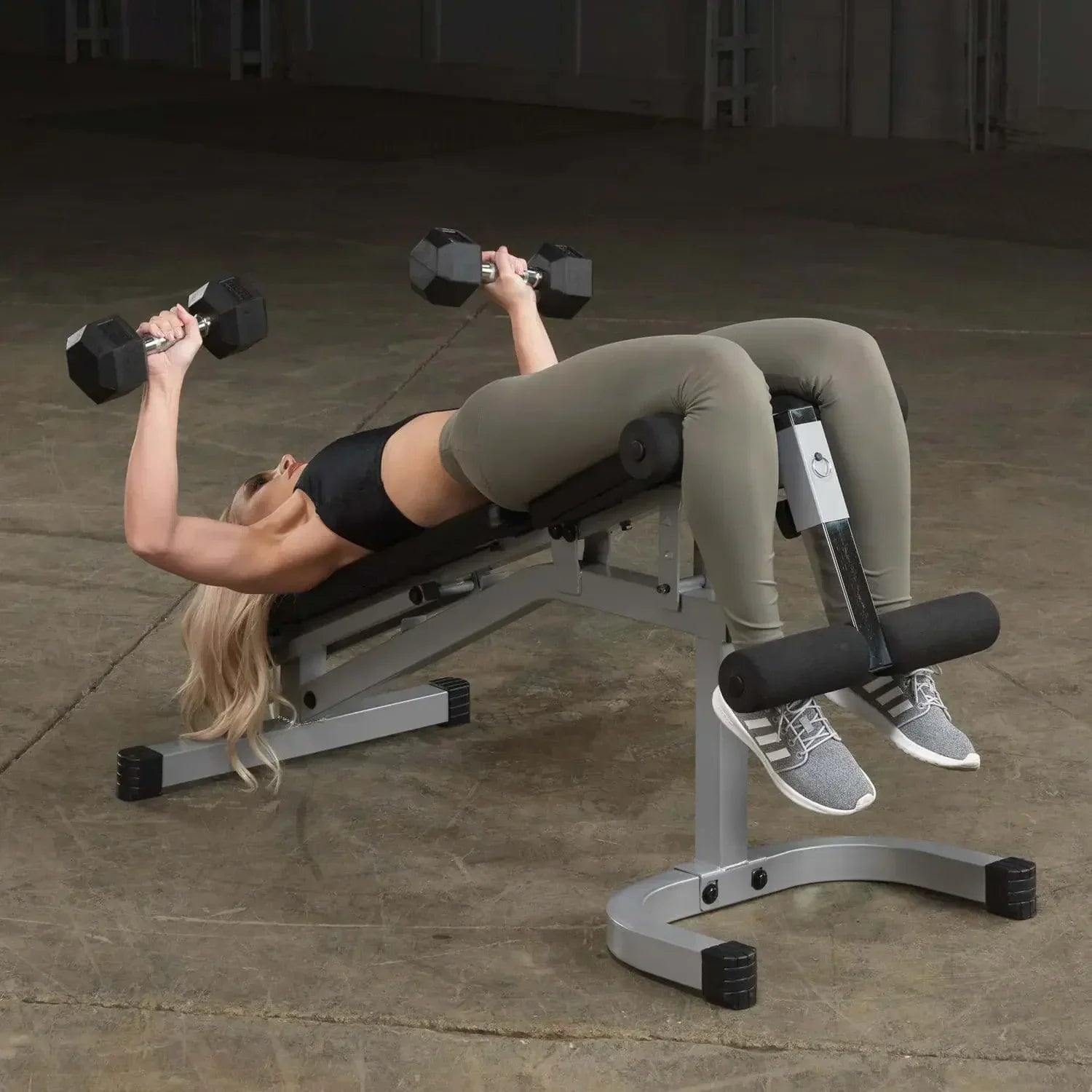Frau trainiert mit Hanteln auf Hantelbank im Fitnessstudio