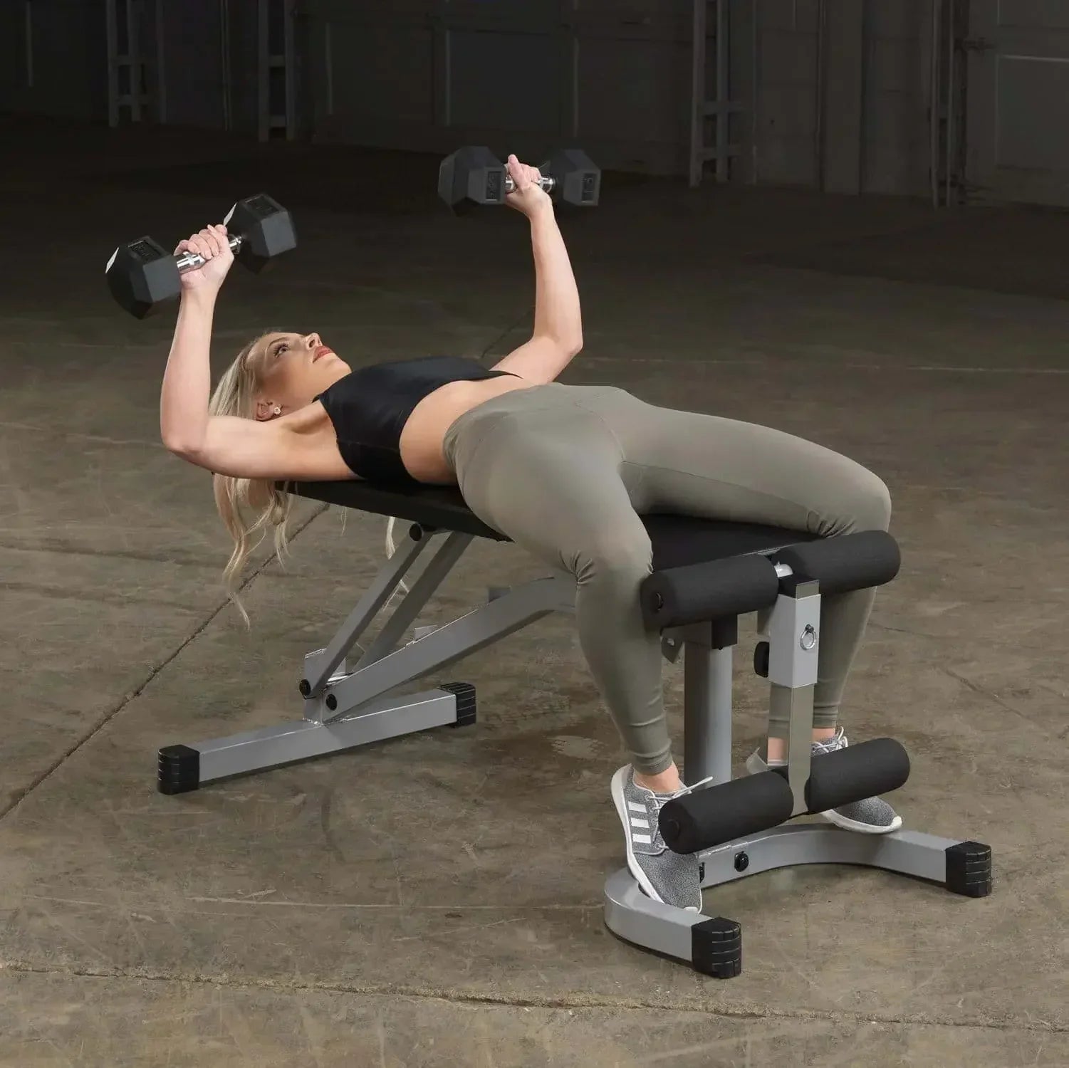 Frau trainiert mit Hanteln auf Hantelbank im Fitness-Studio, ideal für Homegym & Krafttraining