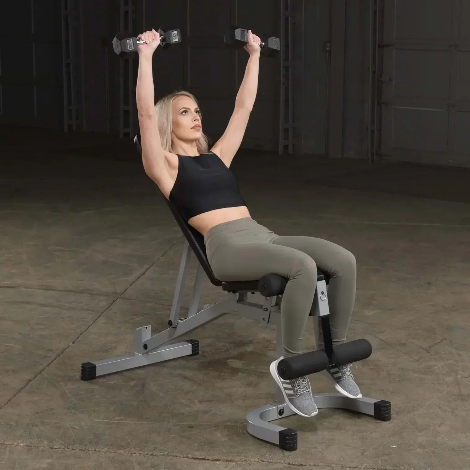 Frau trainiert mit Hanteln auf Hantelbank im Fitnessstudio, ideal für Homegym & Krafttraining