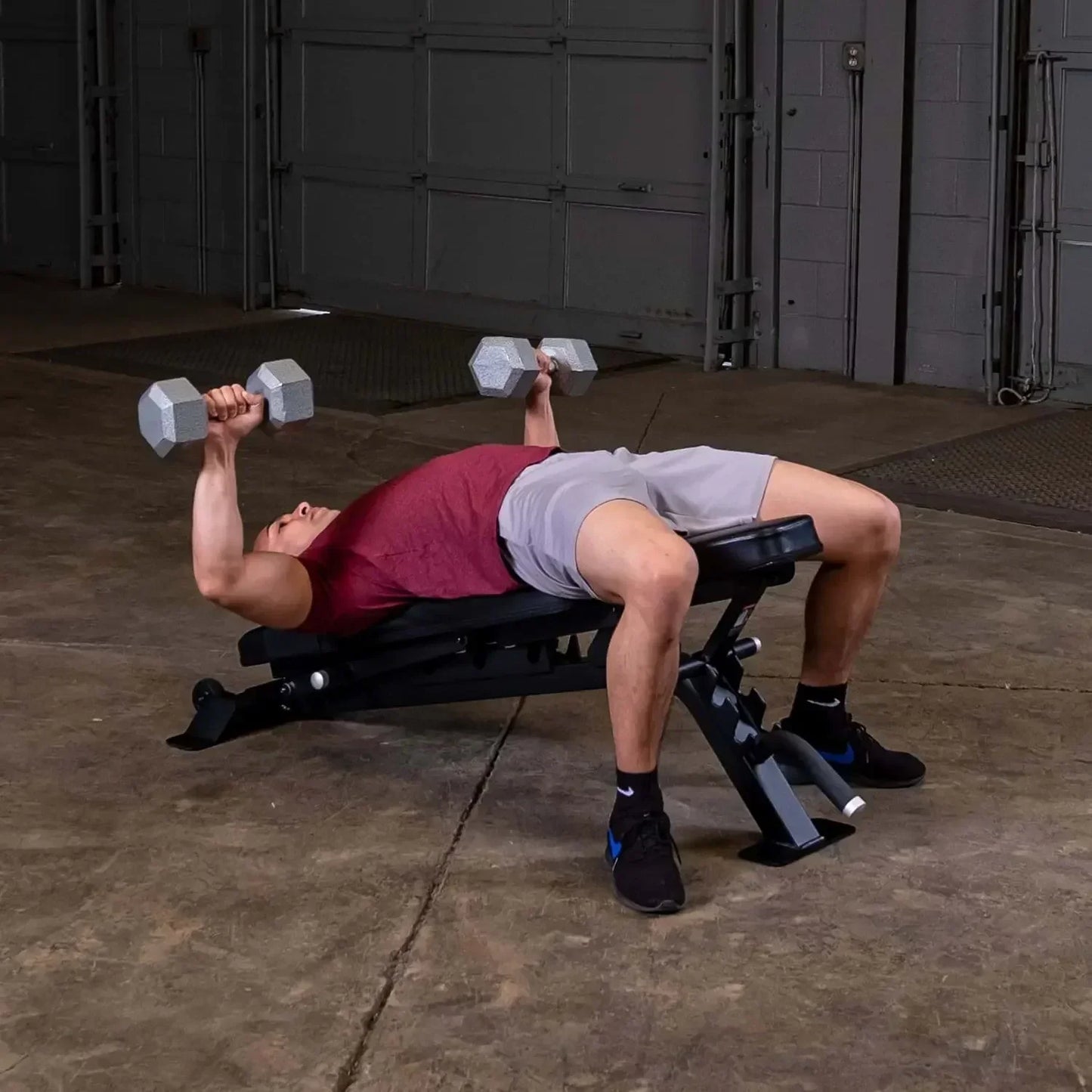 Mann trainiert mit Hanteln auf Hantelbank im Homegym – Kraftsport & Fitness Equipment