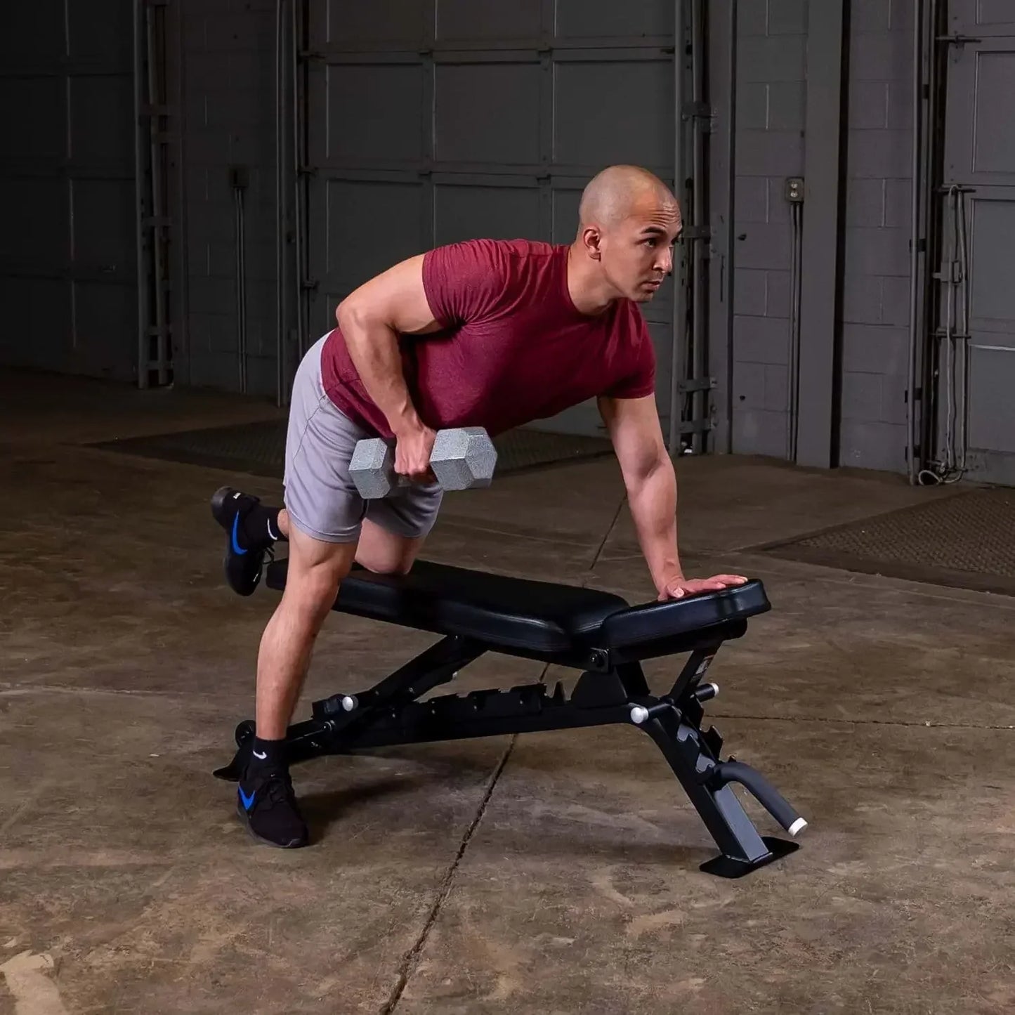 Mann trainiert mit Hanteln auf Fitnessbank im Homegym – Kraftsport & Fitness Equipment