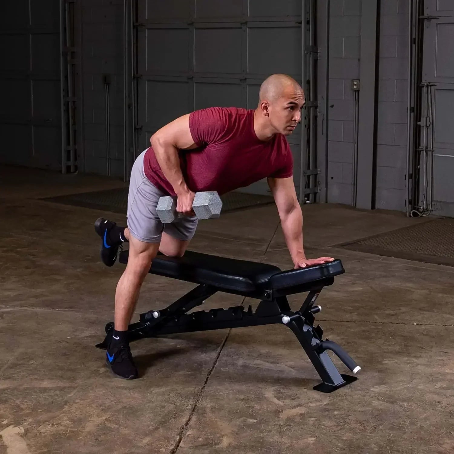 Mann trainiert mit Hanteln auf Fitnessbank im Homegym – Kraftsport & Fitness Equipment