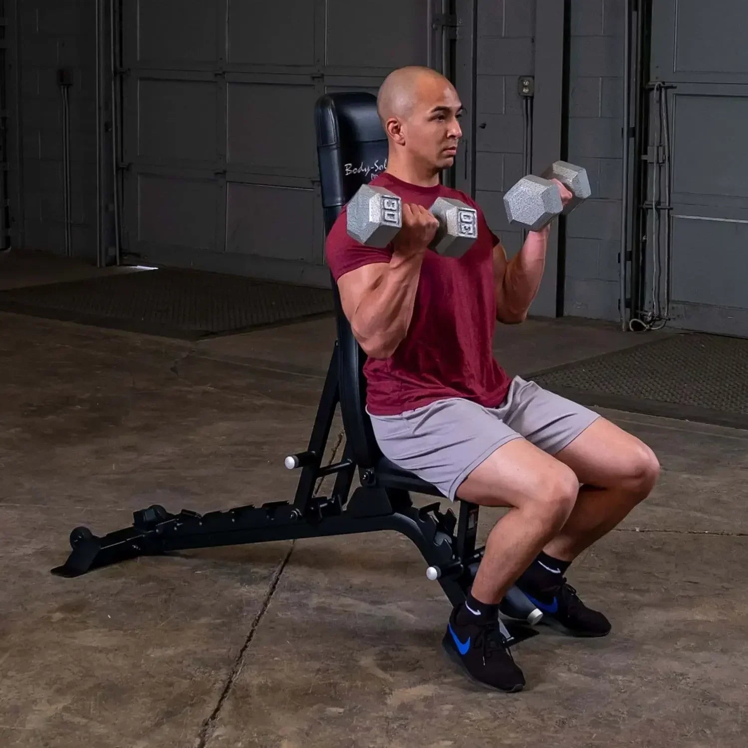 Mann trainiert mit Hanteln auf Hantelbank im Homegym – Kraftsport & Fitness Equipment
