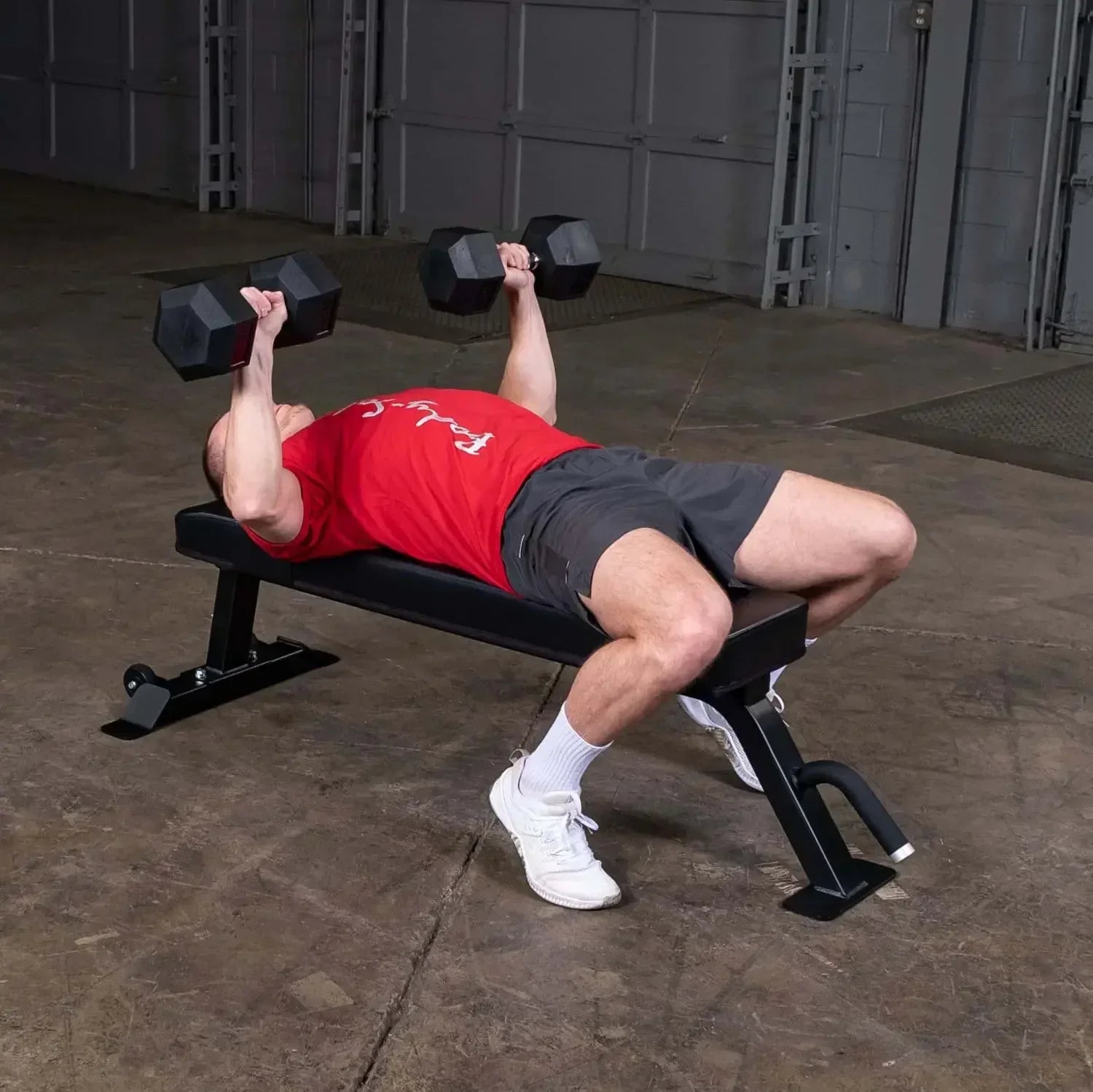 Mann trainiert mit Hanteln auf einer Hantelbank im Fitnessstudio
