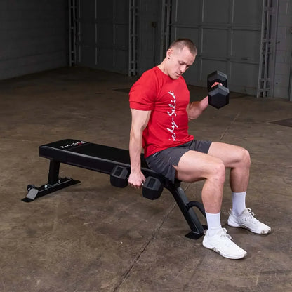 Mann trainiert mit Hanteln auf einer Fitnessbank im Homegym