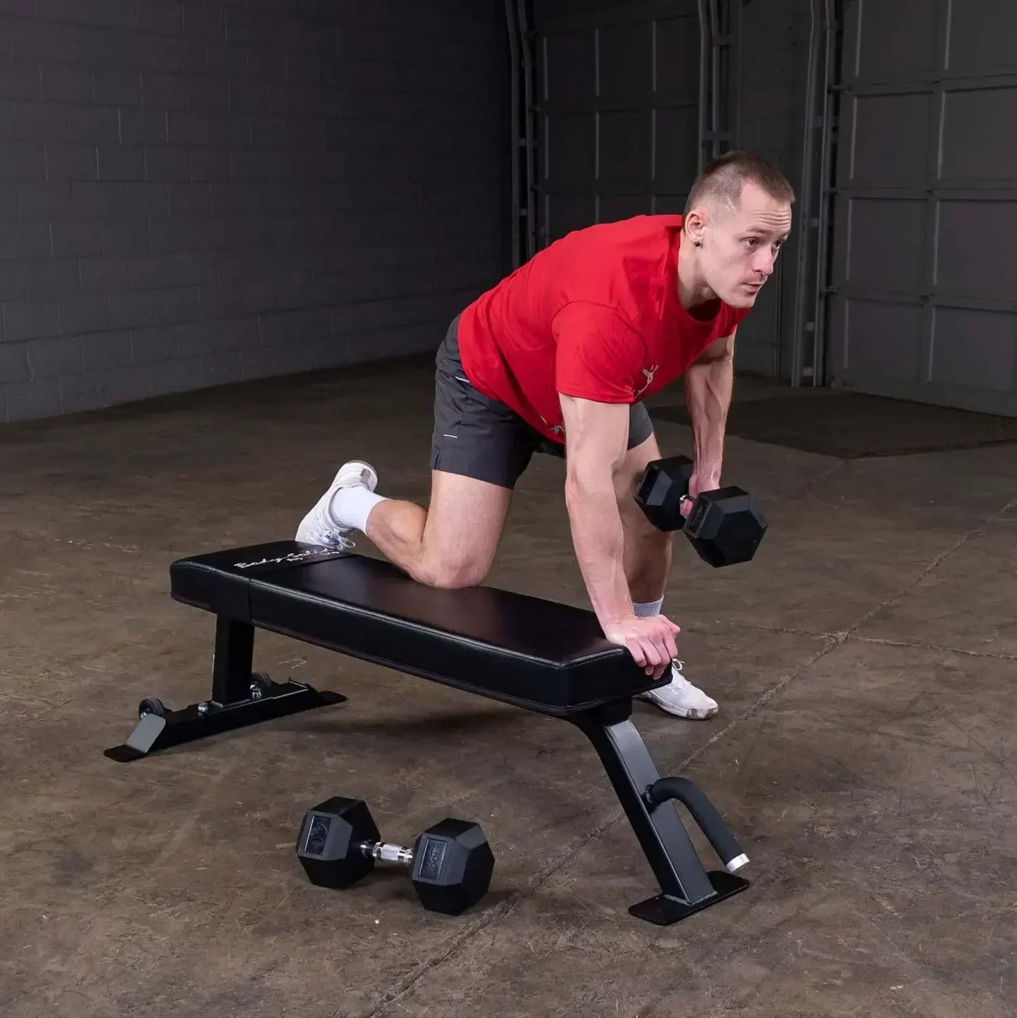 Mann trainiert mit Hanteln auf Hantelbank im Homegym – Kraftsport & Fitness Equipment